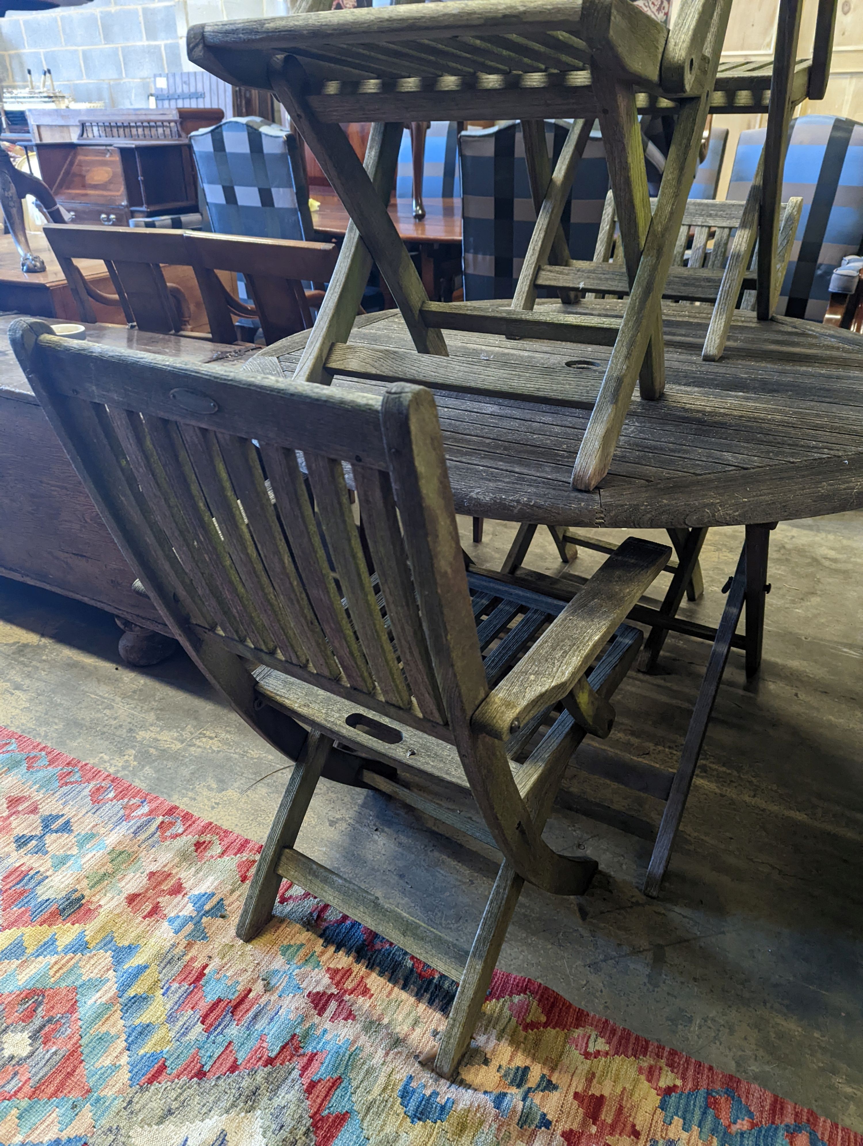 A set of four Westminster teak folding elbow chairs and a weathered teak circular garden table, diameter 120cm, height 73cm